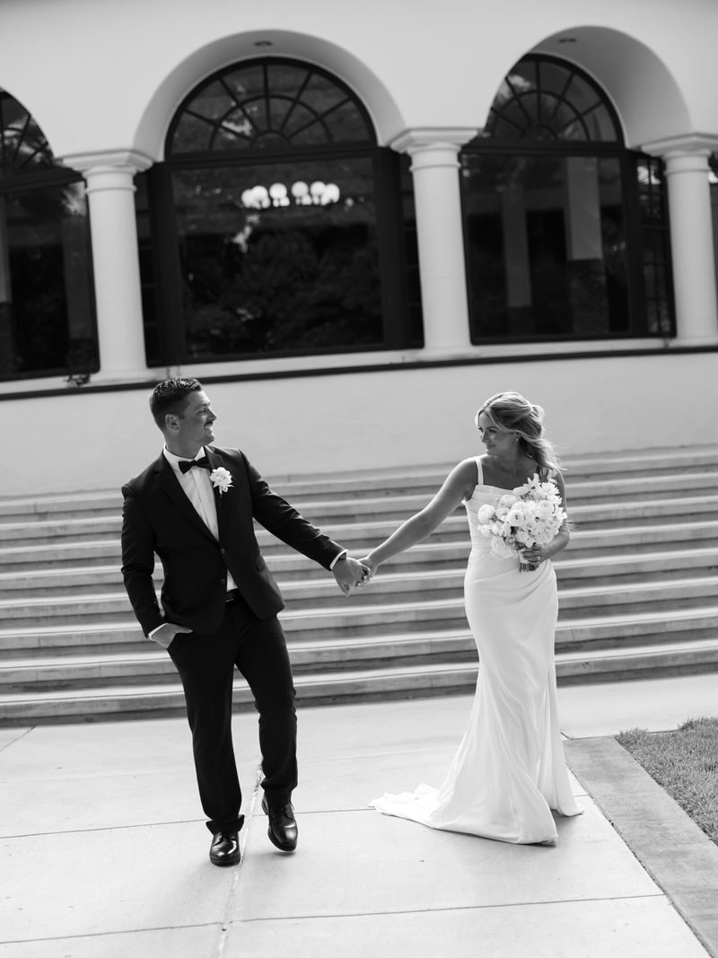 Bride and groom walking hand in hand in black tie